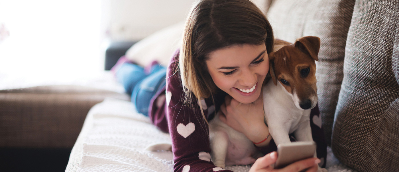 Woman with her dog looking into pet insurance on her mobile phone