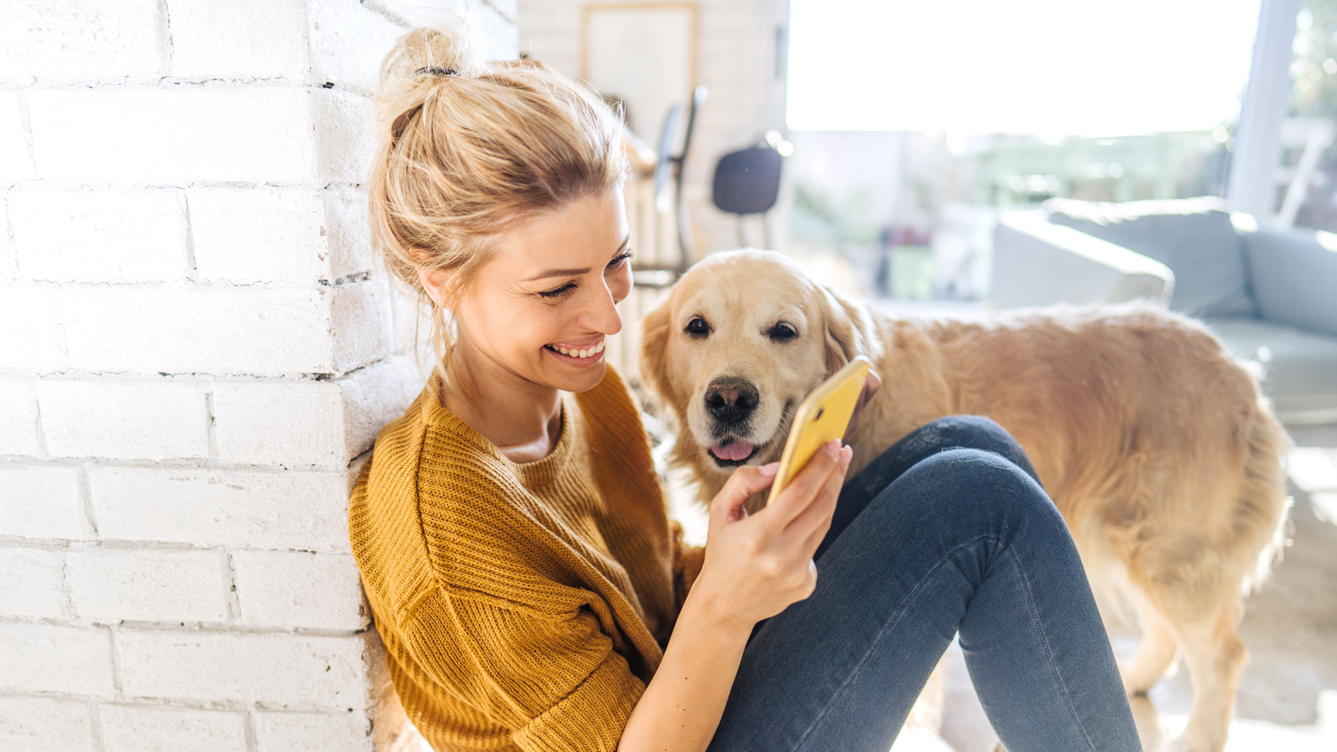 Woman sitting with her dog looking at her phone